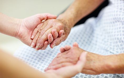 Close up of a nurse holding a patient's hands.