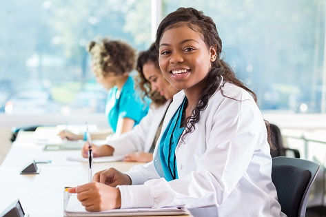 A young, female, African American medical student sits at her desk.