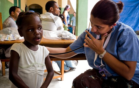 A physician listens to the breathing of a child abroad.