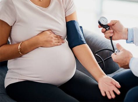 Pregnant woman having her blood pressure monitored by a doctor.