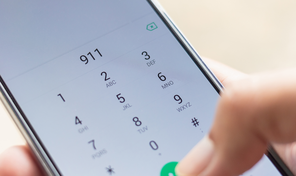 A person dialing 911 on a cell phone