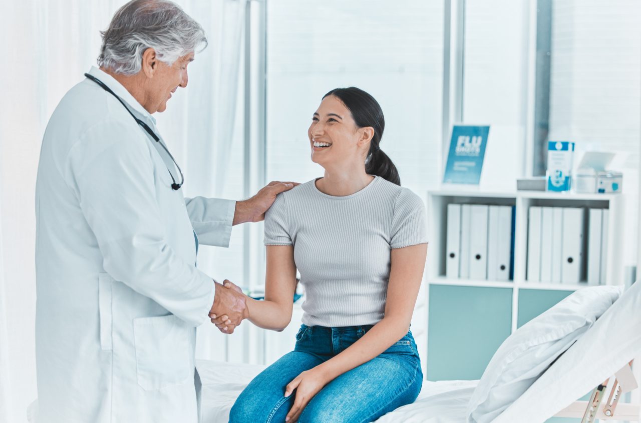 A senior doctor shaking hands with a patient in greeting.