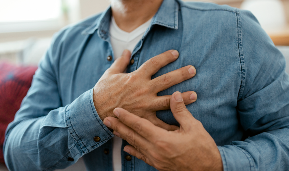 A man clasps his chest with heart pain.