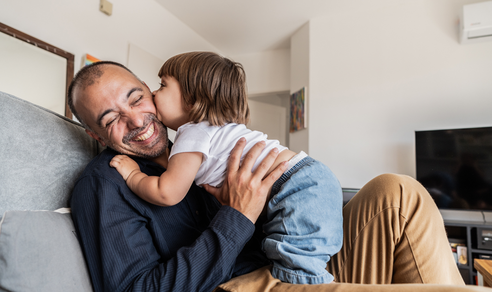 A child kissing their father on the cheek