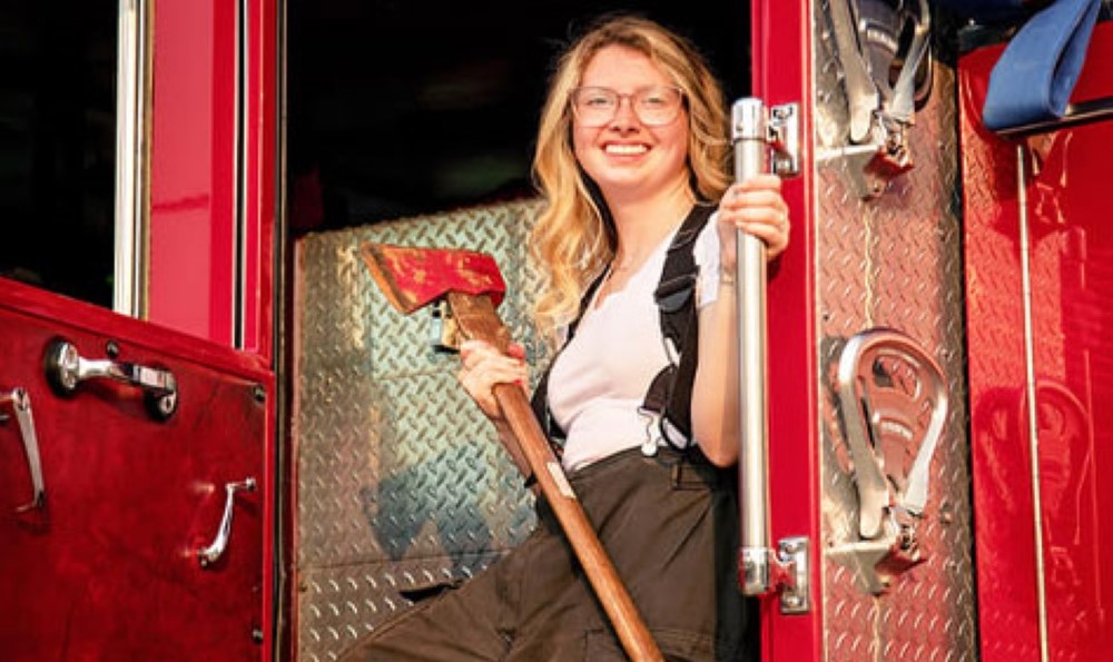 Grace R. stands on a firetruck with an ax after her successful scoliosis revision.