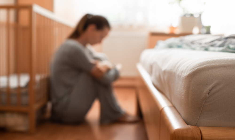 Pregnant woman sitting next to bed