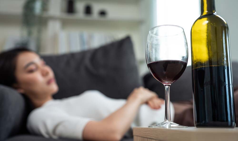 A woman sleeping next to a glass of wine