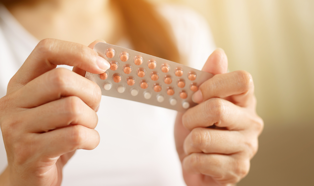 A woman holding a card of birth control pills