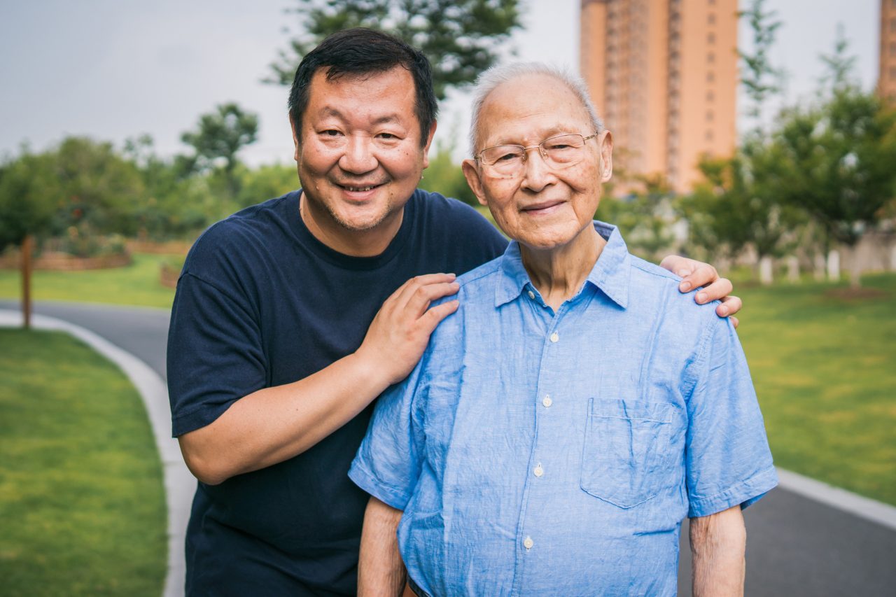 An Asian man cares for his dad with affection.