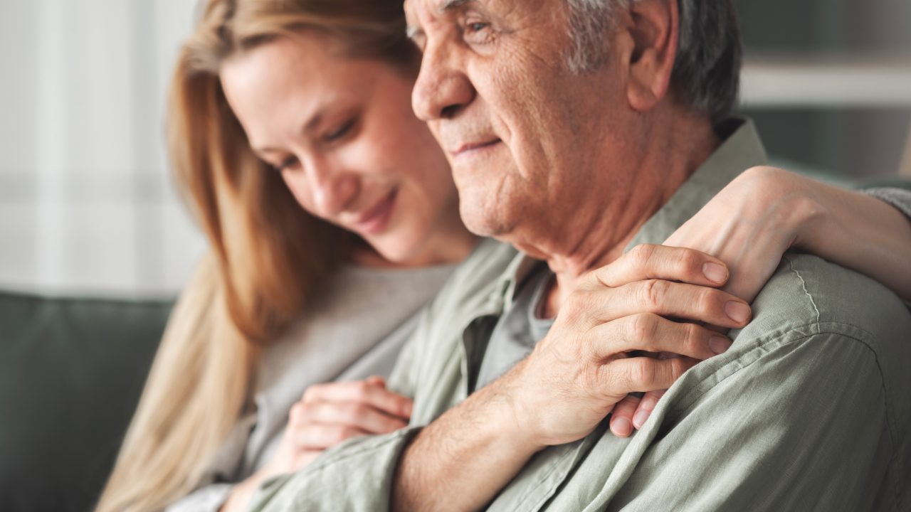 A loving hug at home between adult caregiver and senior parent.