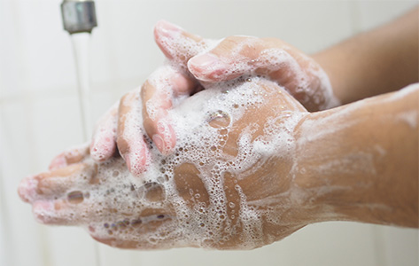 Soapy hands under a faucet.
