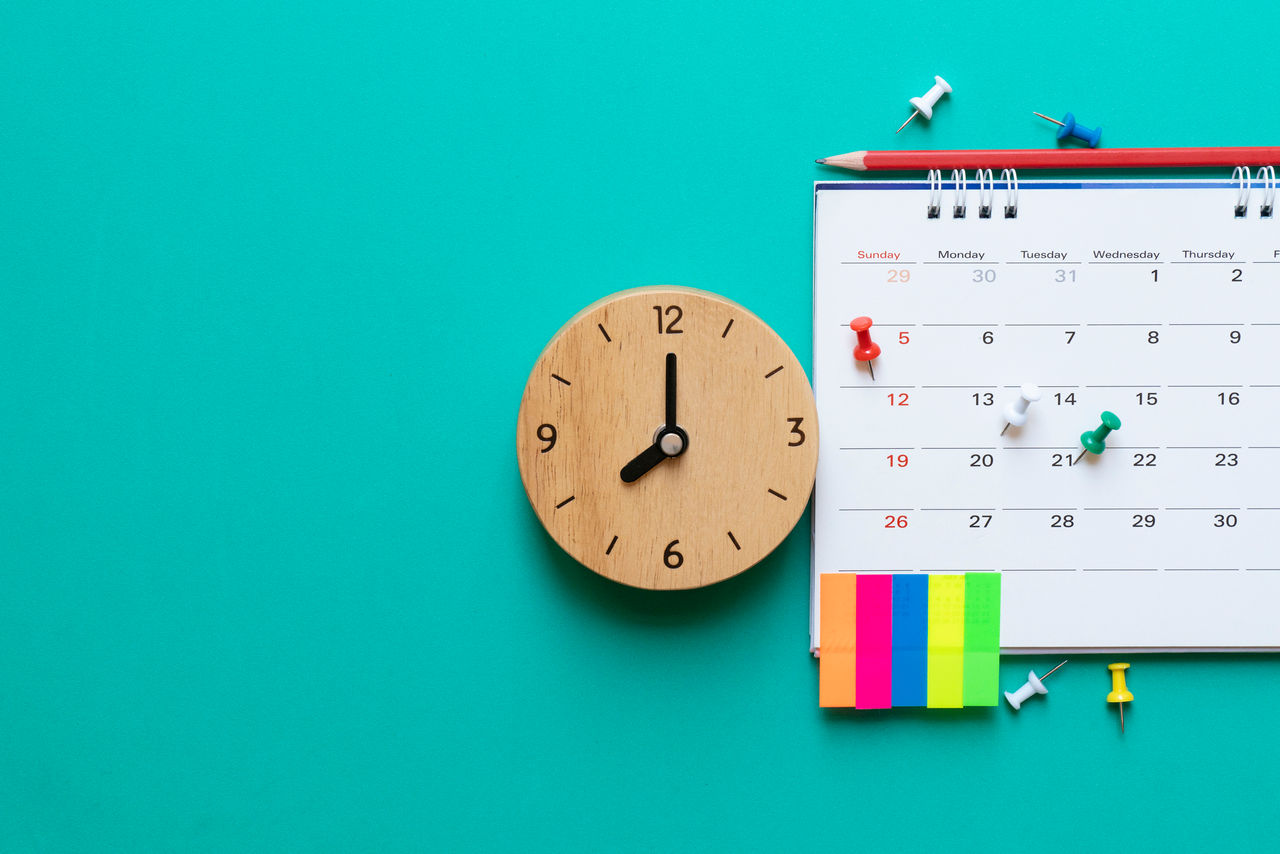 Close up of calendar and clock on green background, planning for cancer classes.