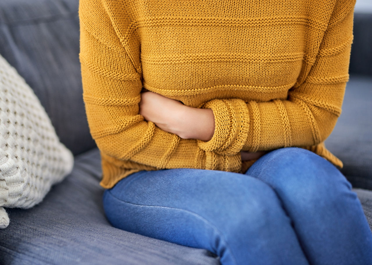 A woman with uterine fibroids grasps her abdomen in discomfort.
